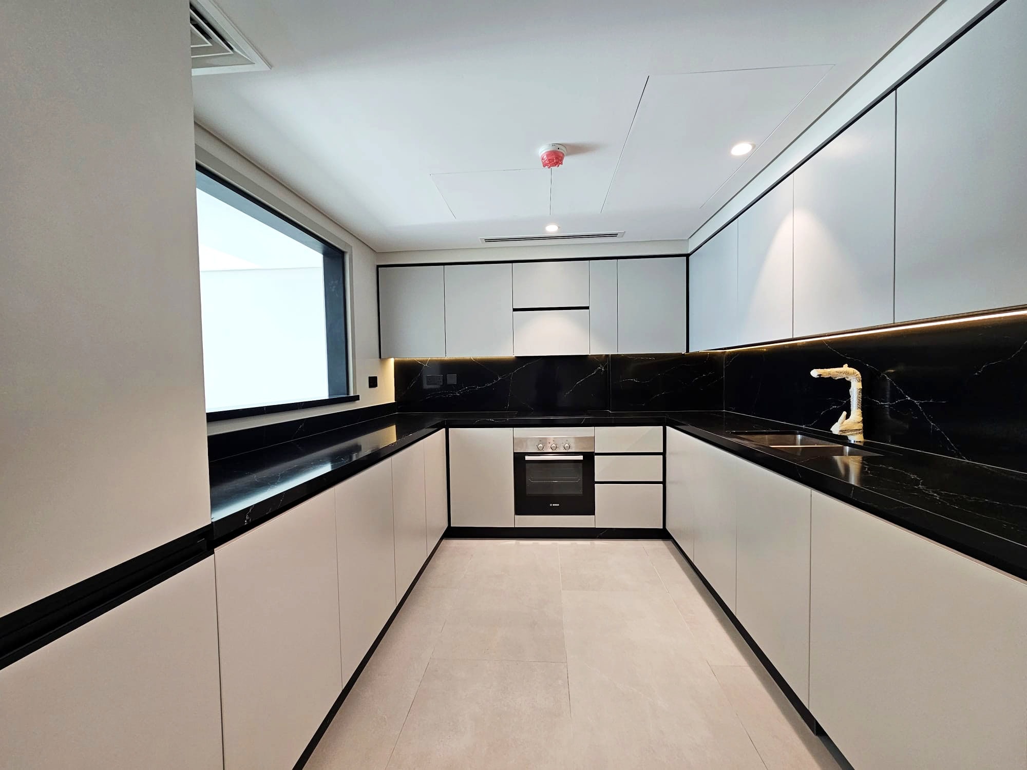 Modern kitchen with black countertops, built-in appliances, and white cabinetry. Auto Draft