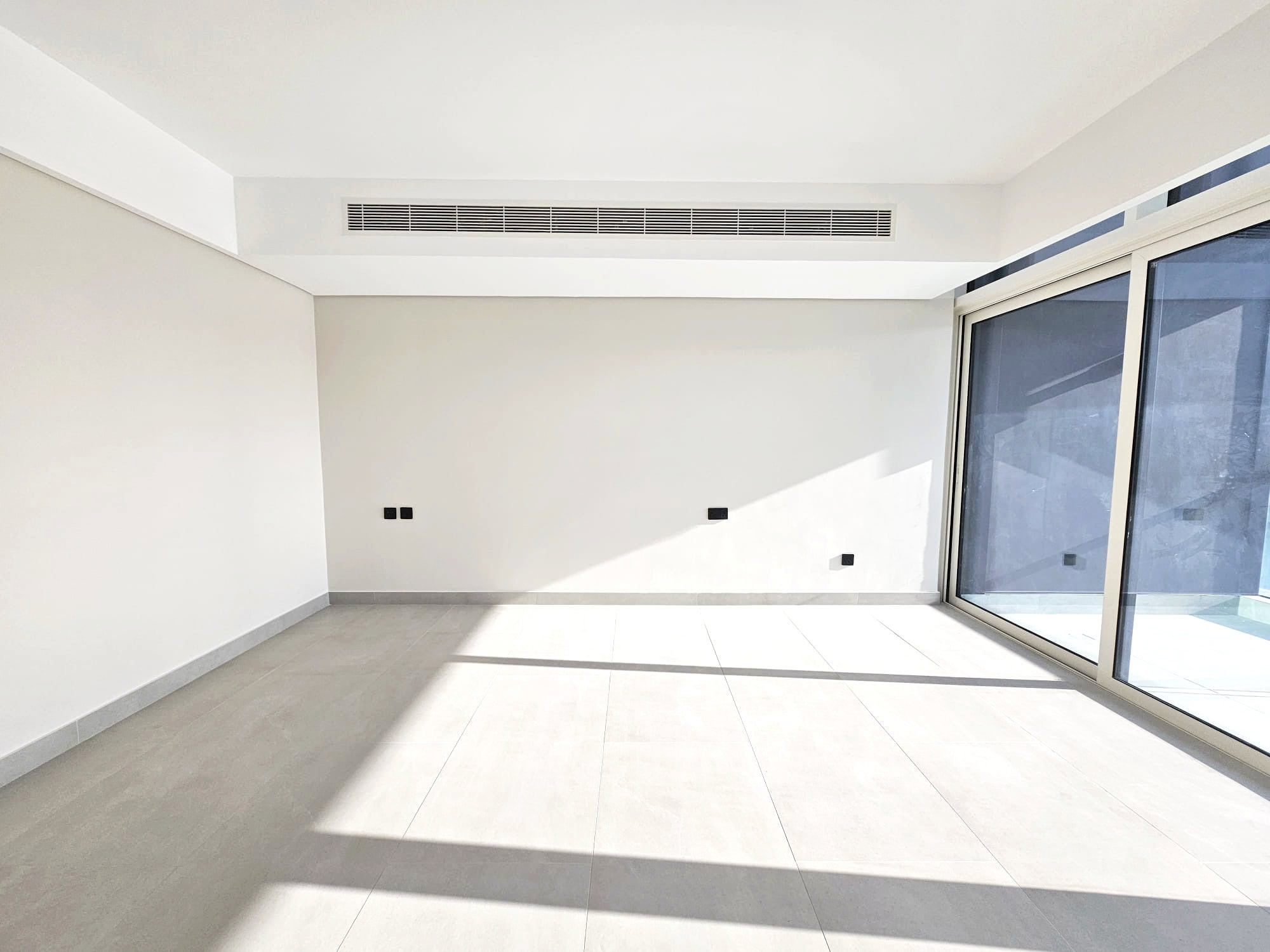 Bright, empty room with large windows, tiled floor, and Auto Draft system.