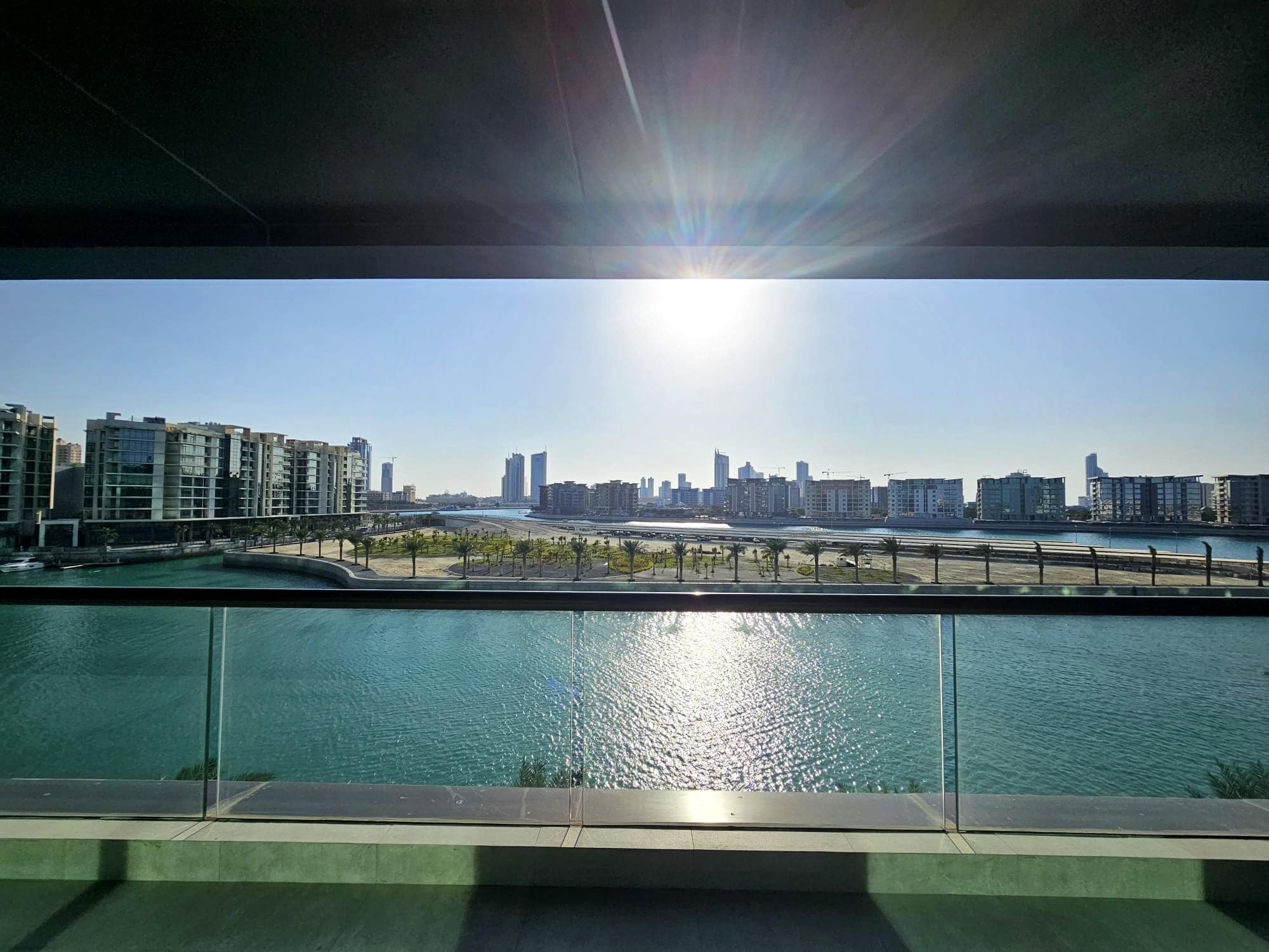 Sunrise over a modern cityscape viewed from a balcony with a river in the foreground. Auto Draft