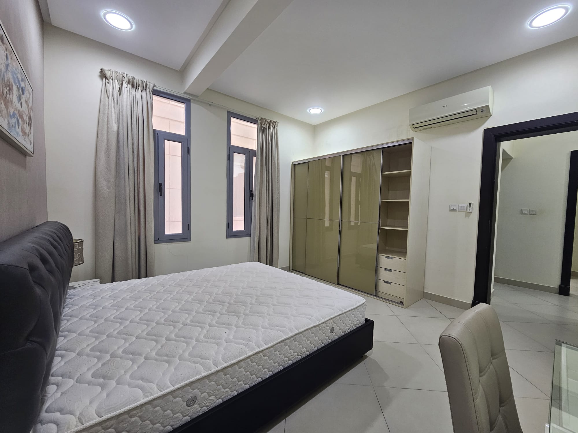 A modern 2BR flat in Adliya, furnished with a large bed, built-in wardrobes, split air conditioning, and neutral color tones. Internet included.