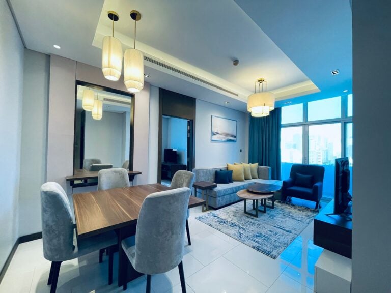Modern living room in a 1BR Apartment with dining area featuring eye-catching, contemporary furniture and pendant lighting in Juffair.