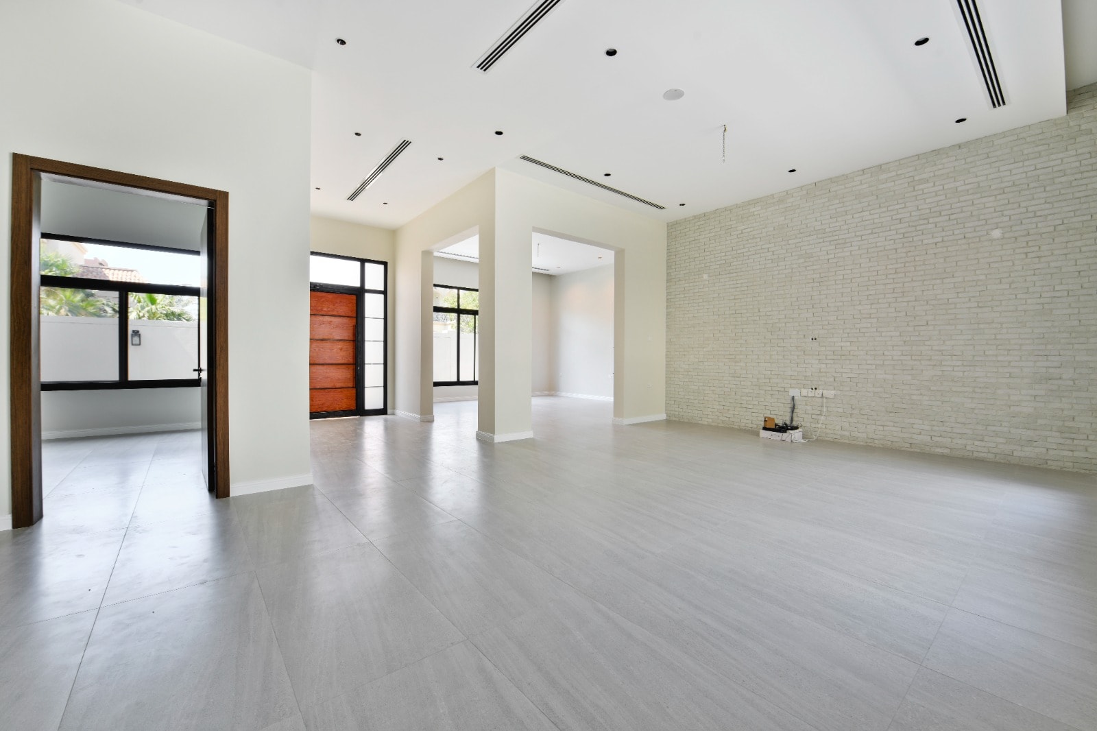 Spacious and modern empty Auto Draft room with white walls, gray flooring, and ample natural light.