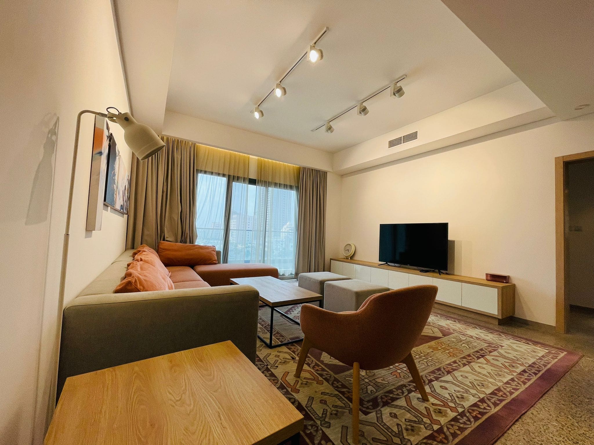 Modern living room in a luxury 1 BR apartment in Juffair with a comfortable seating area, television, and warm lighting.