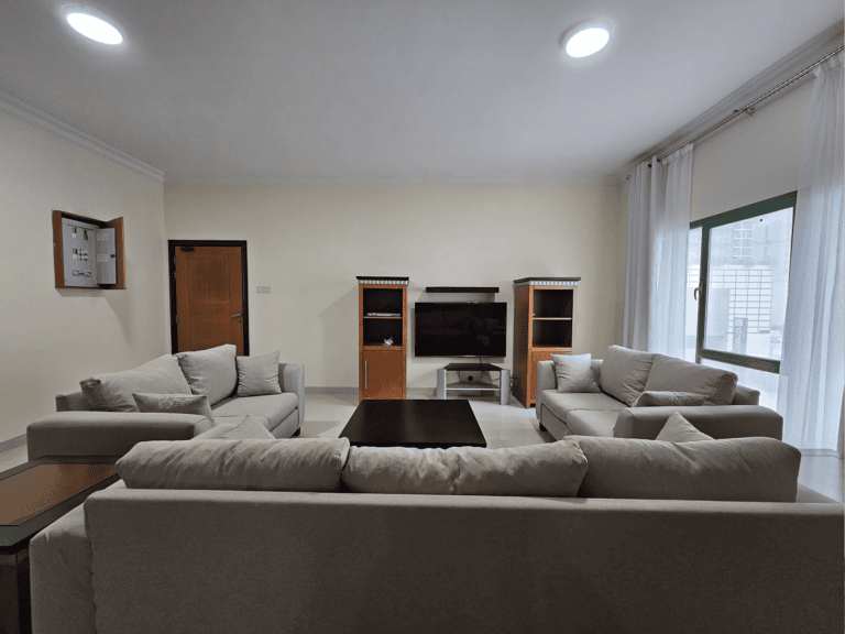 Modern 3 BR apartment for rent in Juffair, featuring a living room with two sofas and a television stand.