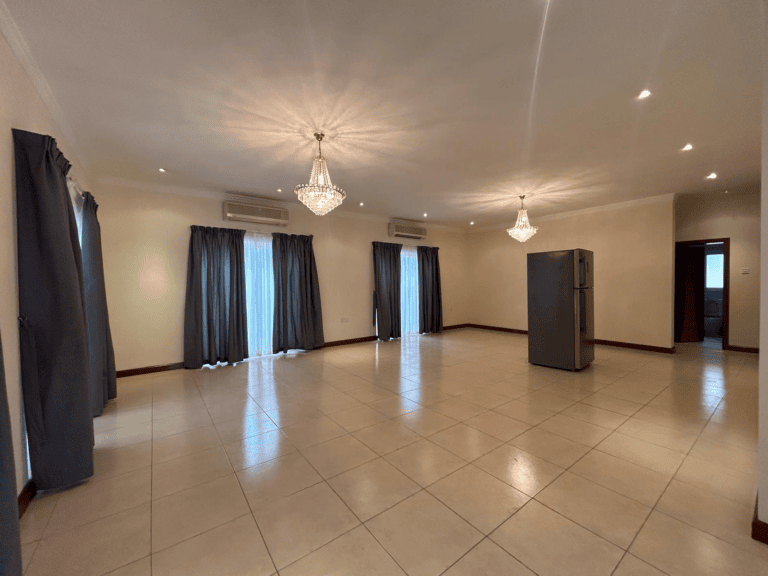 Spacious, empty 3 BDR Villa for rent with tiled floor, two crystal chandeliers, gray curtains, and a fridge near a doorway in Saar Area.