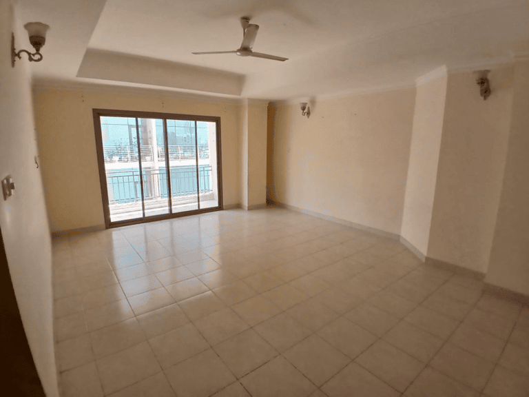 Empty living room with tiled floor, two ceiling fans, and a large window balcony door overlooking a view in Al Hidd.