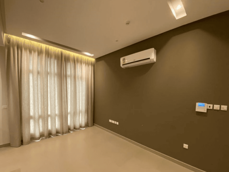 Luxury apartment room with a grey wall, featuring an air conditioner, white sheer curtains, and dim ceiling lights.