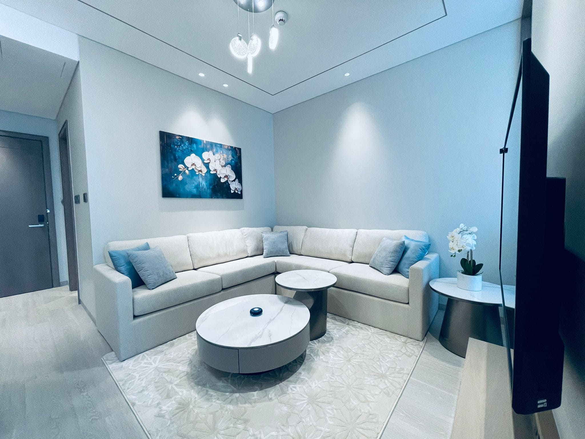 An amazing apartment living room with an L-shaped sofa, a round coffee table, and wall art.