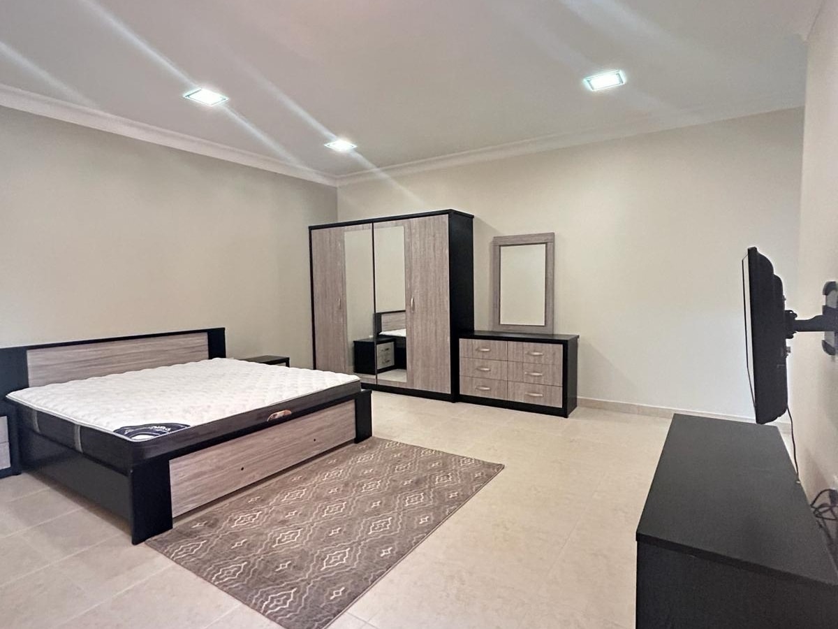 A modern bedroom with a large bed, a wardrobe, a dresser with a mirror, and Auto Draft on a stand, featuring tiled flooring and recessed ceiling lights.