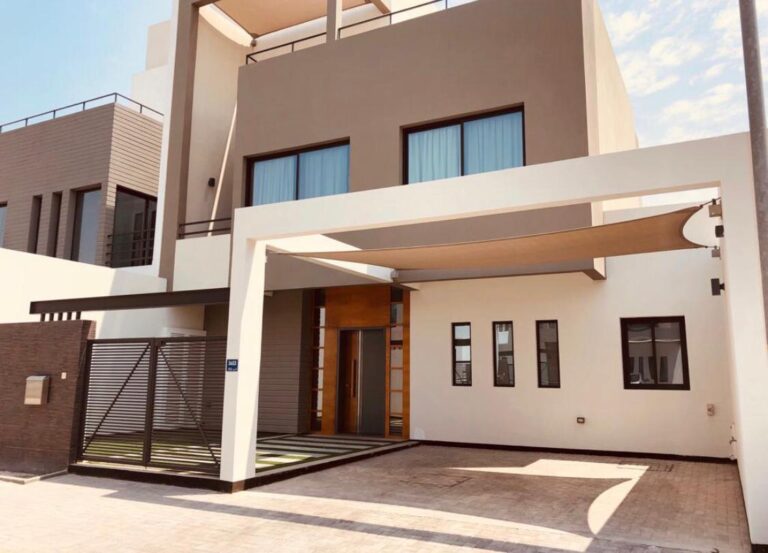 Modern two-story luxury villa in Saar with a beige exterior, large windows, and a covered driveway.