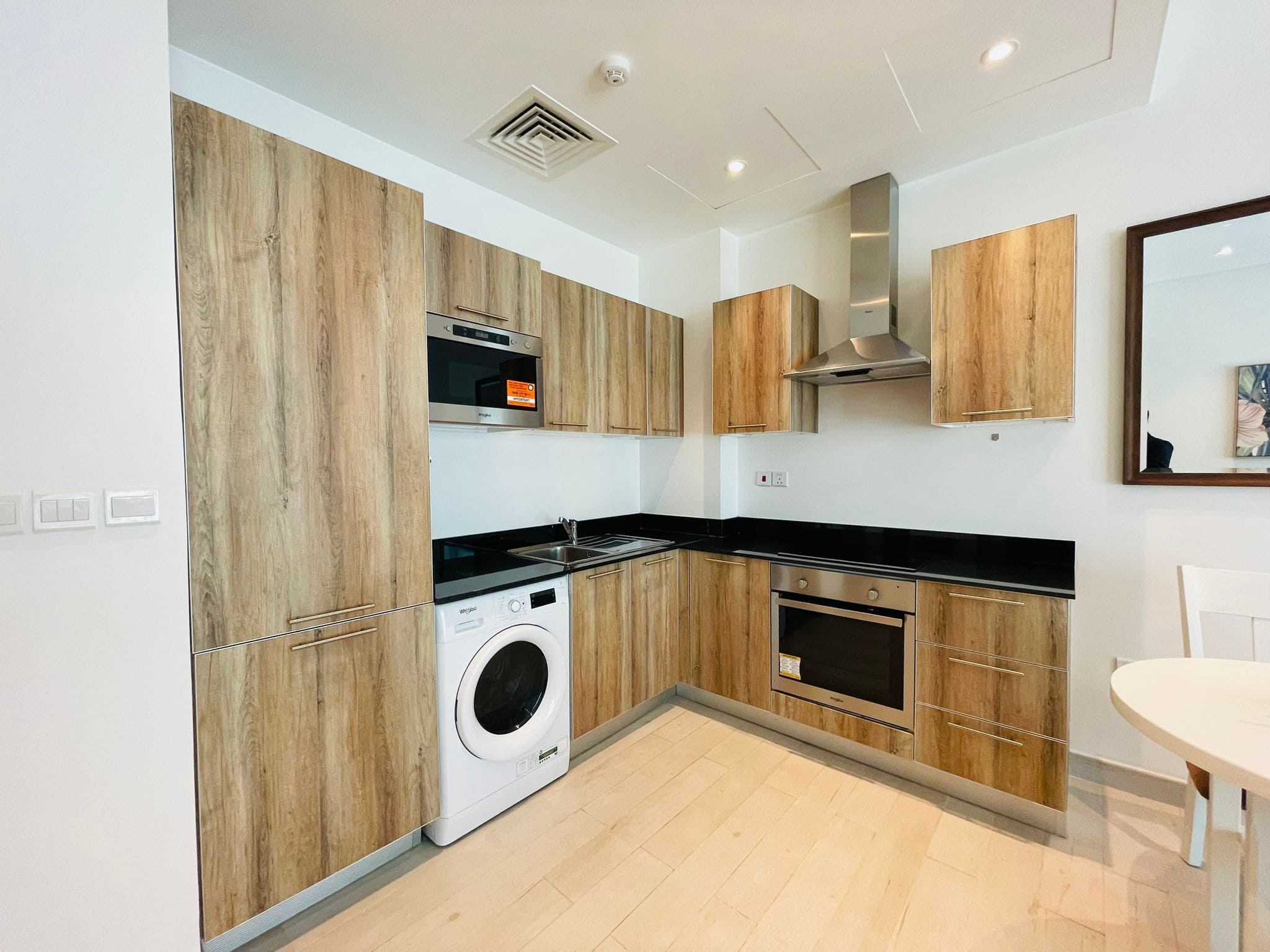 Stylish apartment with modern kitchen interior, wooden cabinets, built-in appliances, and a washing machine.