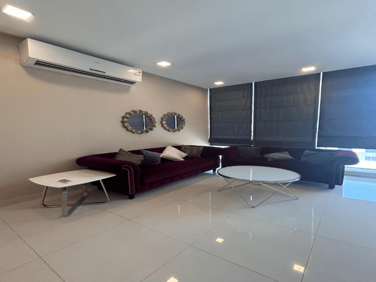 Modern living room in a luxury apartment with a red sofa, white coffee tables, and round mirrors on the wall, under an air conditioner unit.