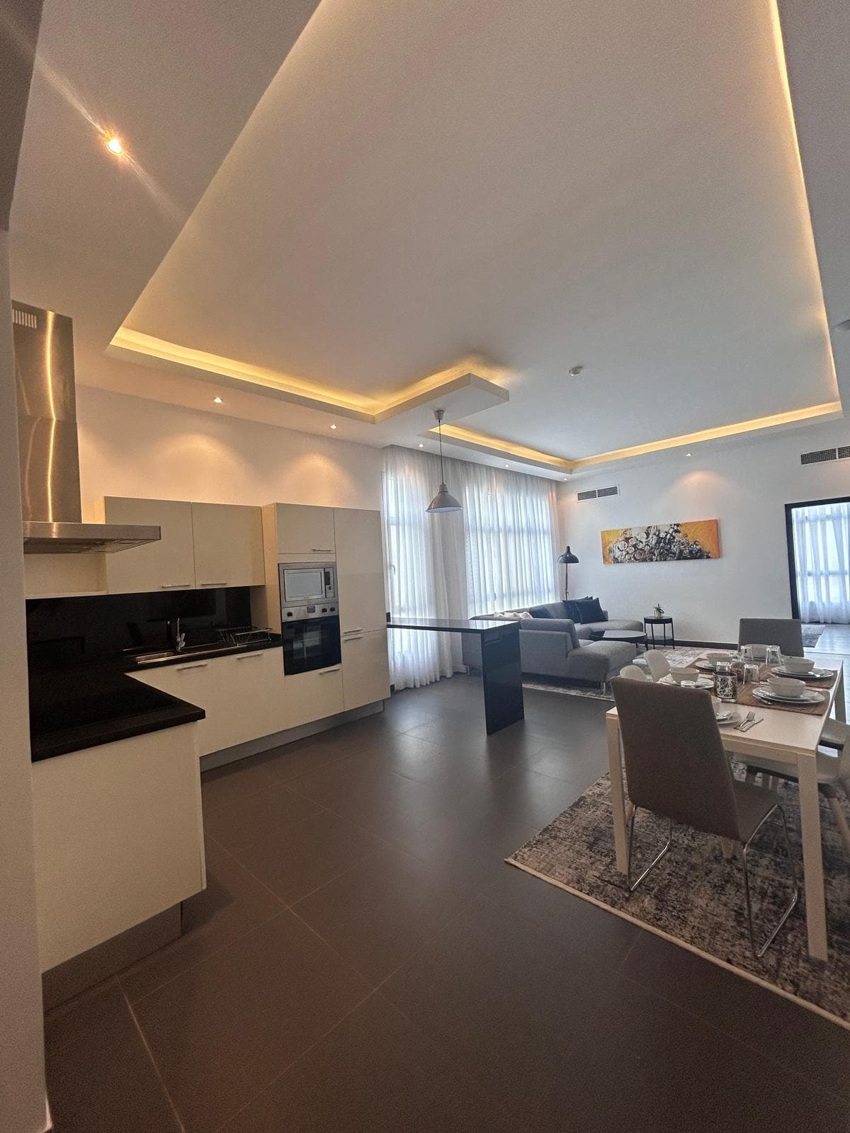 Luxury open-plan apartment interior with a kitchen, dining area, and living room, featuring neutral colors and contemporary furnishings.