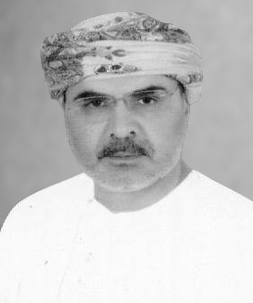 A man wearing traditional Middle Eastern clothing and a patterned headscarf stands confidently, looking directly at the camera. This striking image captures the essence of cultural pride, reminiscent of House Me Bahrain's vibrant identity in the heart of Bahrain.