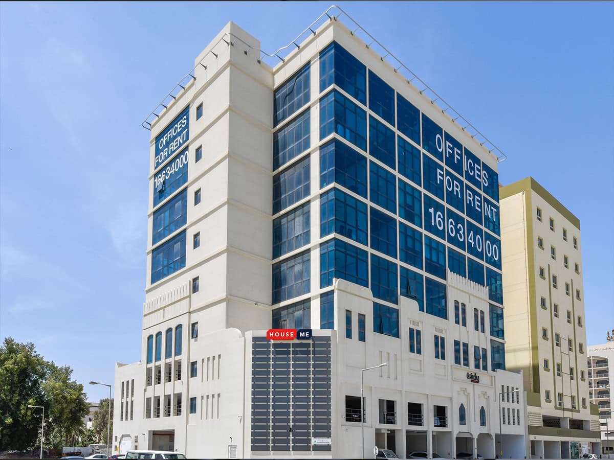 This exclusive modern multi-story office building with large windows boasts prominent "Offices for Rent" signage. Surrounded by other structures and lush vegetation, it offers a prime location for businesses seeking to maximize ROI on their investment.