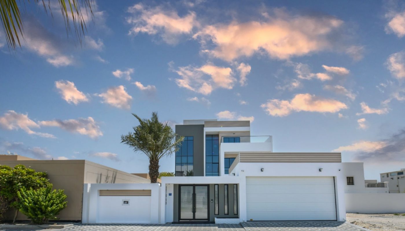 A modern house with a garage and palm trees for sale in Janabiyah.