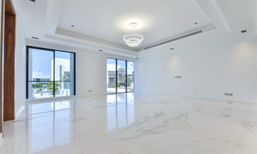 A white marble floored living room with large windows in a fancy 5BR villa for sale.