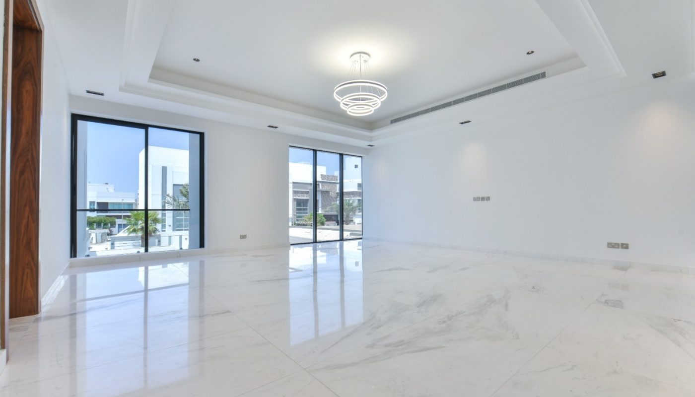 A white marble floored living room with large windows in a fancy 5BR villa for sale.