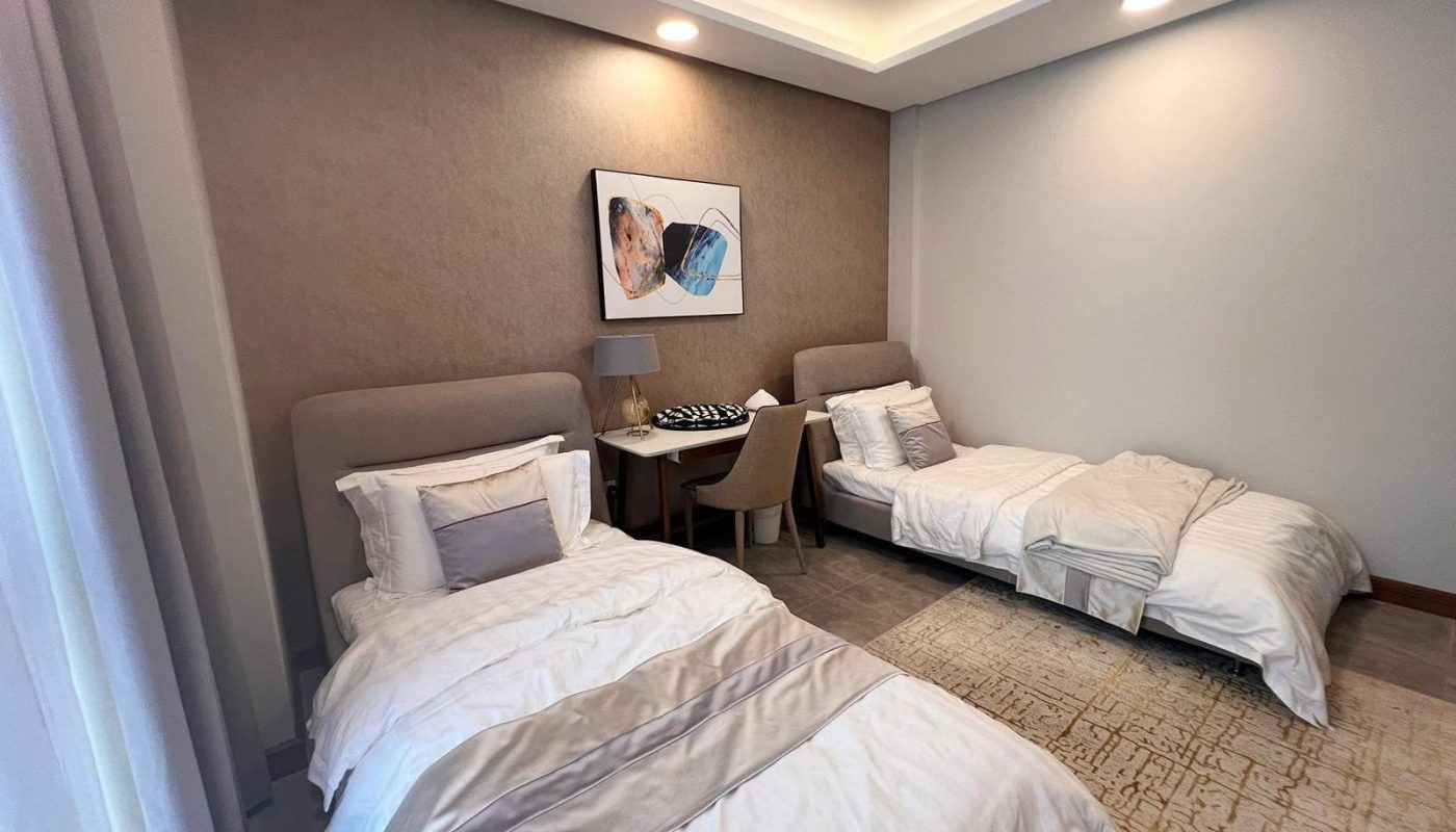 Luxurious flat for sale with two beds in a room with white walls.