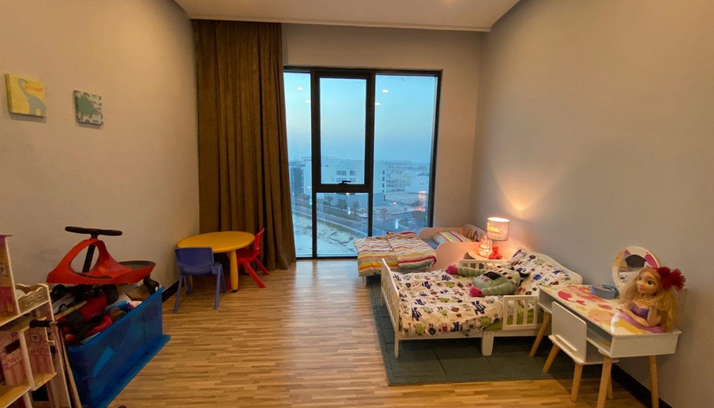 Amwaj apartment for sale featuring a child's room with toys and a view of the city.