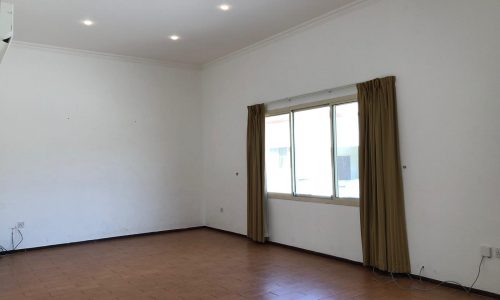 An empty room with tiled flooring, white walls, a window with closed beige curtains, and several recessed ceiling lights.