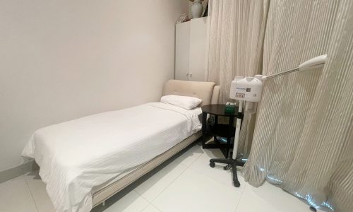 A hospital room with a single bed, bedside equipment, auto draft, and curtains.