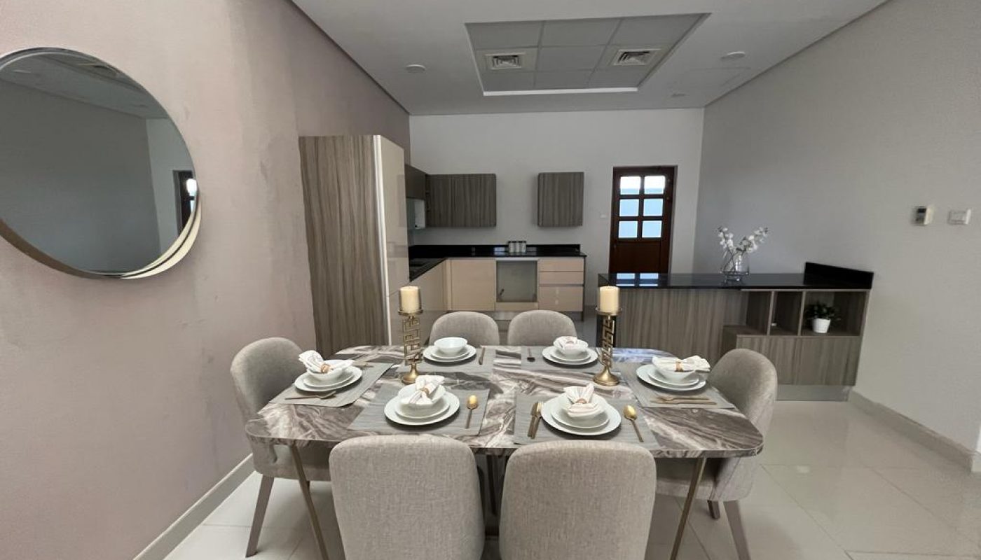 A dining room with a table and chairs in a new luxury villa for sale with a balcony.