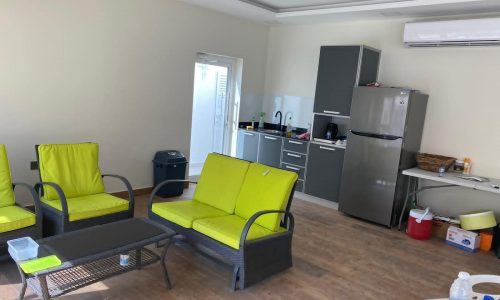 A modern, bright kitchenette with green sitting area.