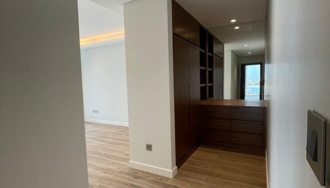 A Dilmunia apartment hallway with wood floors and white walls.