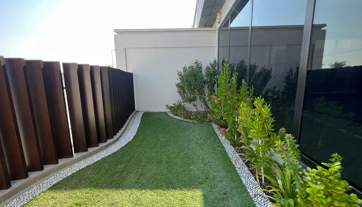 A small garden with grass and plants in front of a luxury building.