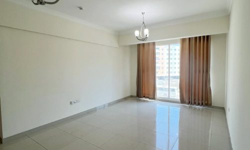 An empty room with tiled floors, a large window, and 2 bedrooms.