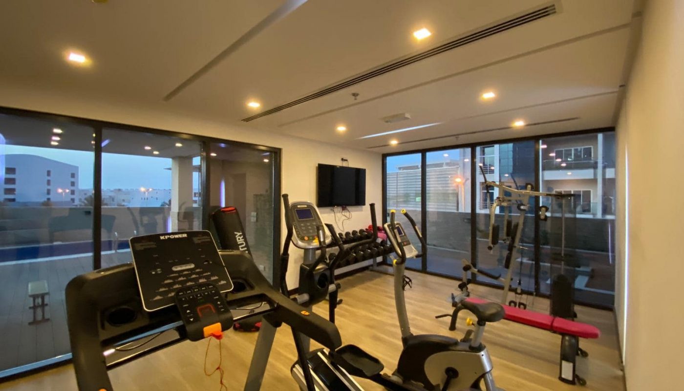 An apartment with a gym room equipped with exercise equipment and large windows is available for sale in Amwaj.