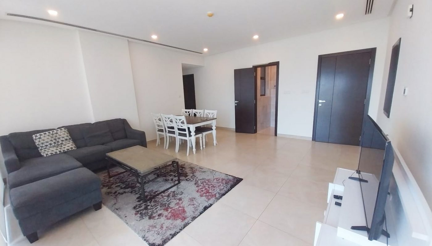 A luxurious apartment with a living room featuring a comfortable couch and a large TV.