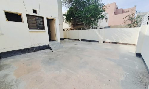 A small backyard with a concrete floor and a fence is available for sale in Hamad Town.