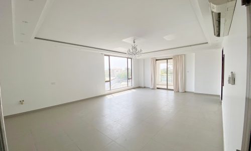 An empty living room with a sliding glass door in an amazing 6BR Villa for sale in Al Markh at the Best Price.