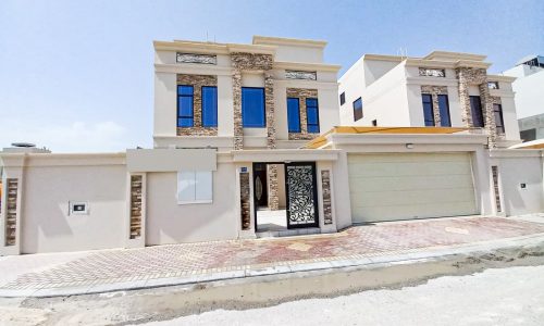 A luxury three story villa with a garage in front of it.