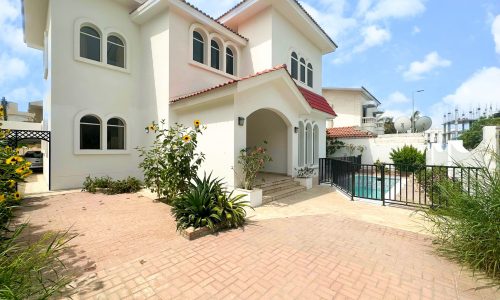 A large white villa with a spacious driveway.