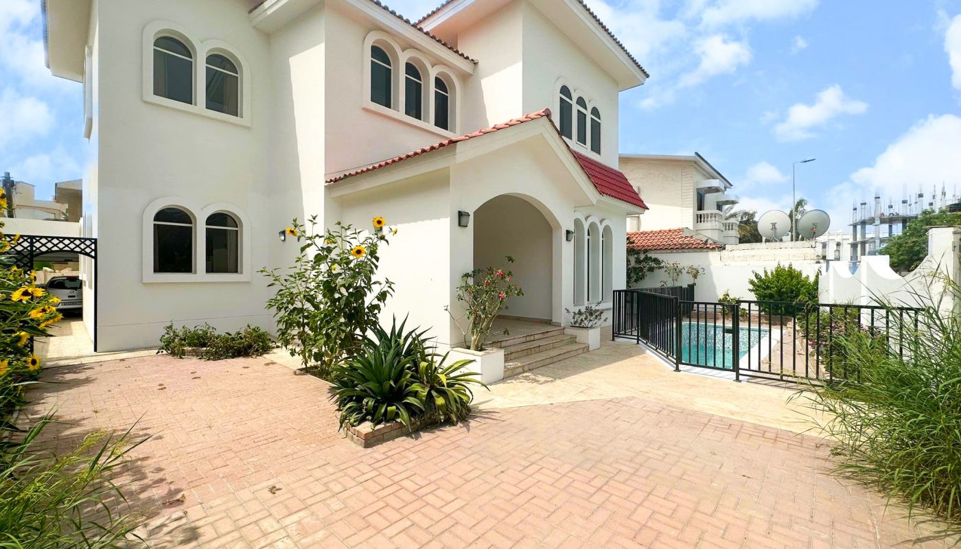 A large white villa with a spacious driveway.