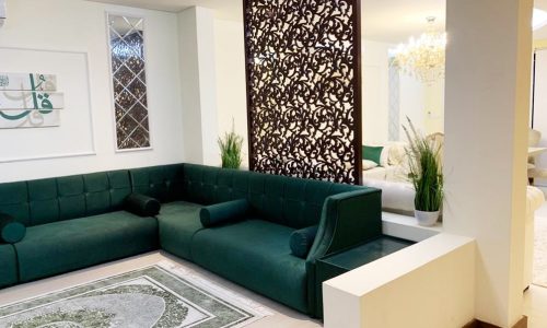 A living room with green couches and a green rug in an amazing 5BR Villa in Al Shurooq | Diyar Al Muharraq.