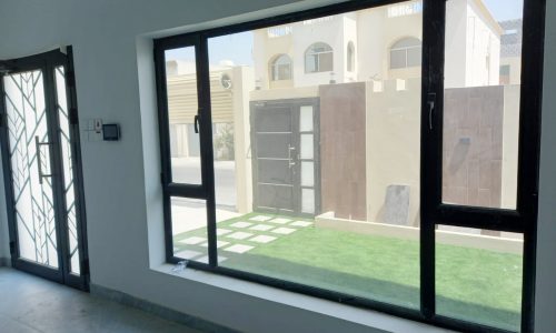 A stunning 5BR villa for sale in Tubli featuring a glass door and a grassy area.