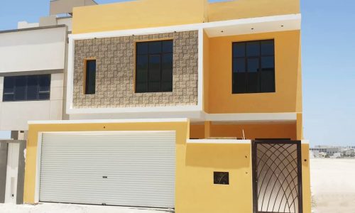 A yellow house in a amazing location with a garage in front of it.