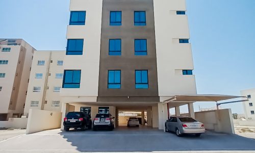 Residential apartment building with cars parked in front.