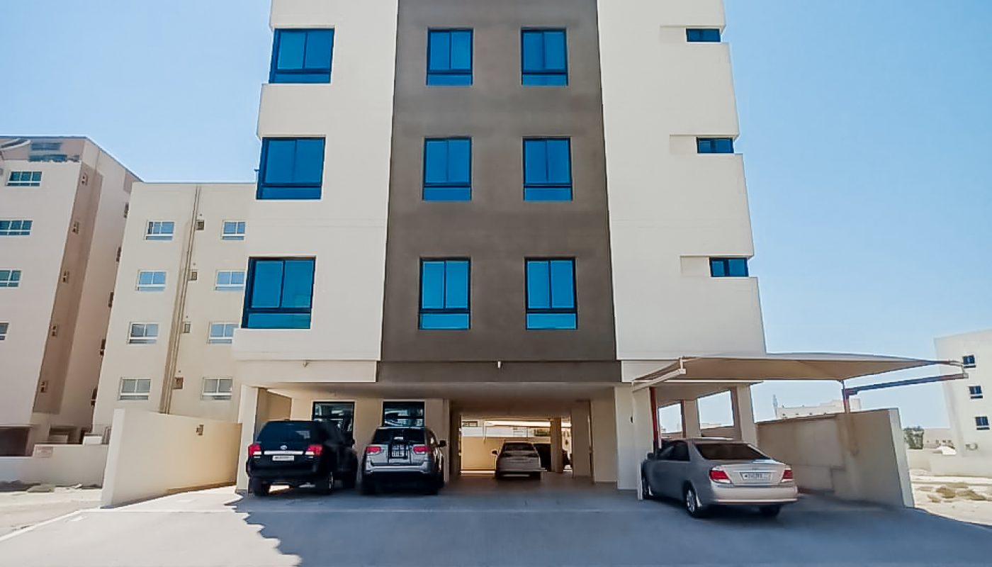 Residential apartment building with cars parked in front.
