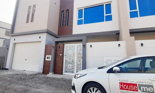 A great white car is parked in front of a modern house.