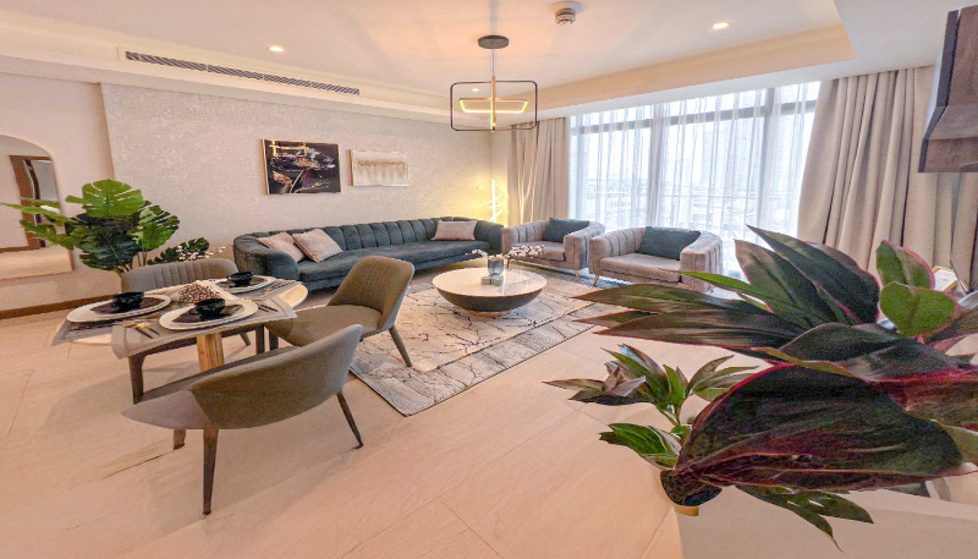 Modern living room with large windows, a sectional sofa, a coffee table, indoor plants, a dining area for two, and contemporary decor in neutral tones.