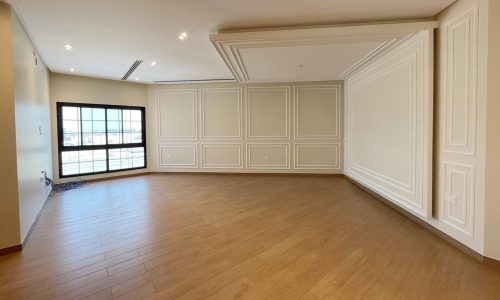 A spacious, empty room with light wood flooring, beige paneled walls, recessed lighting, and a large window letting in natural light creates the perfect palette for an auto draft of design ideas.