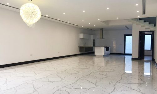 Luxury private villa for rent in Saar, featuring an empty room with marble floors and a chandelier.