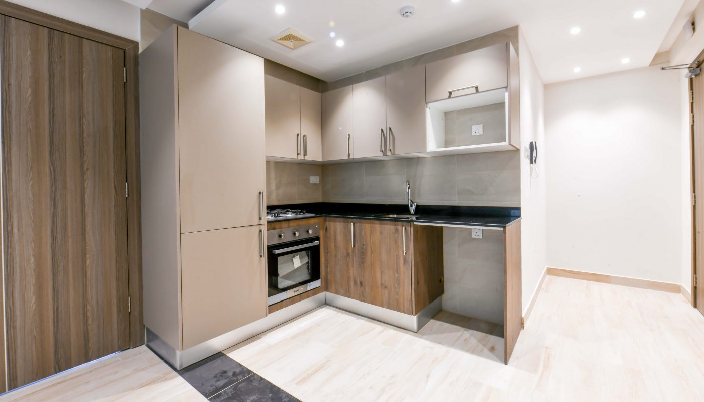 A small kitchen in a spacious apartment with wooden cabinets and a stove.