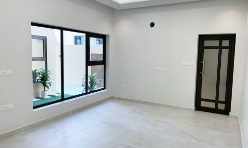 An empty room with a sliding glass door located in a stunning villa for sale in Barbar.