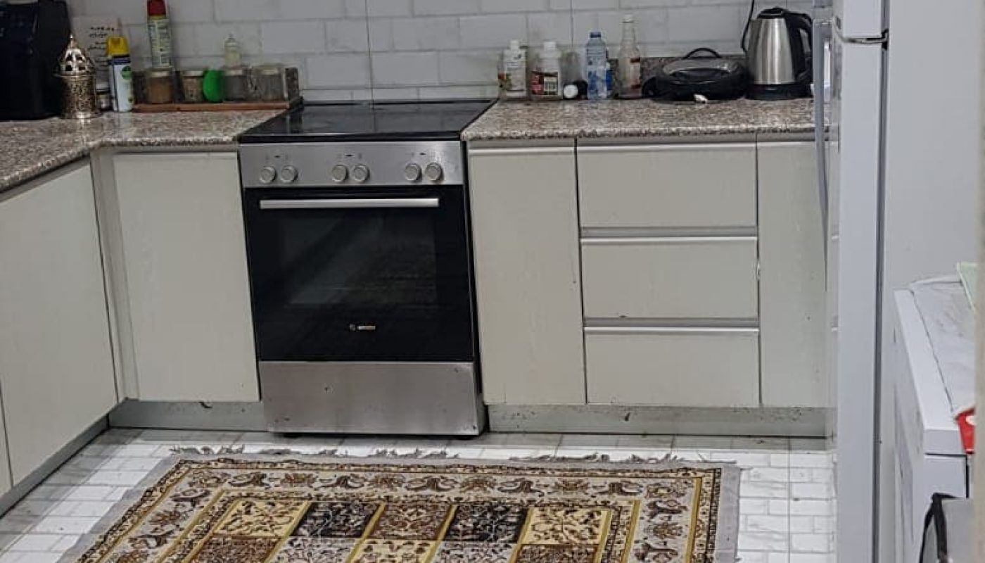 A furnished kitchen with a rug and a refrigerator.